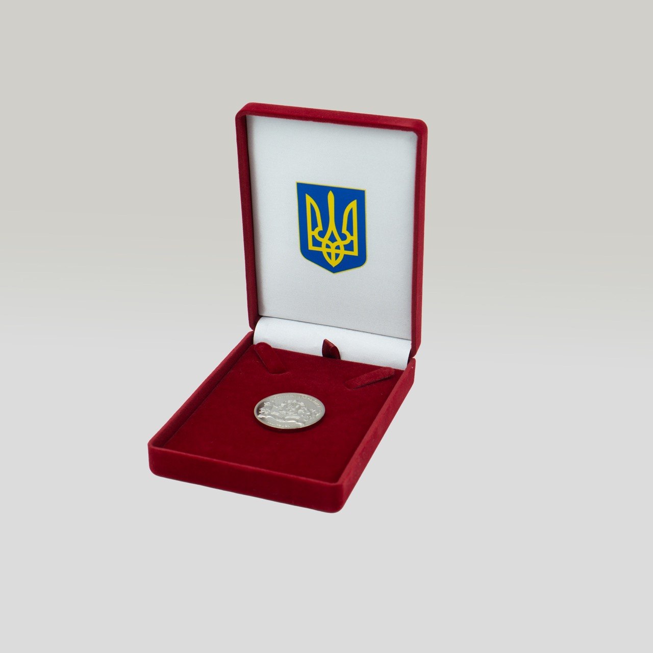 Оксамитовий бордовий футляр з тризубом і срібною медаллю всередині